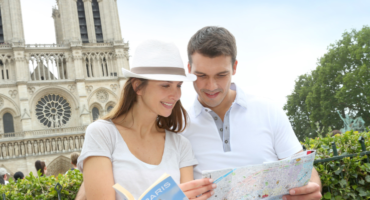 turista pred katedralo Notre Dame v Parizu, gledata turistični vodnik in zemljevid mesta