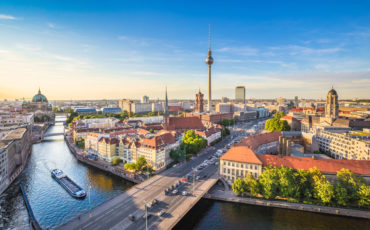 panorama berlina s televizijskim stolpom v ozadju, ob reki, kjer pluje ladja